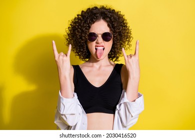 Photo Portrait Of Curly Female Rocker Showing Heavy Metal Sign Tongue Wearing Sunglass Top Shirt Isolated On Bright Yellow Color Background