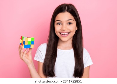 Photo portrait of cute schoolgirl solving task puzzle play game rubik cube wear trendy white outfit isolated on pink color background