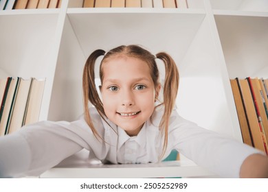 Photo portrait of cute small schoolgirl inside book shelf library take selfie photo playful home education concept school interior - Powered by Shutterstock