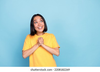 Photo portrait of cute young girl korean hold hands together look copyspace dressed stylish yellow look isolated on blue color background