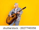 Photo portrait of elder woman playing acoustic guitar on festival feeling young isolated vivid yellow color background