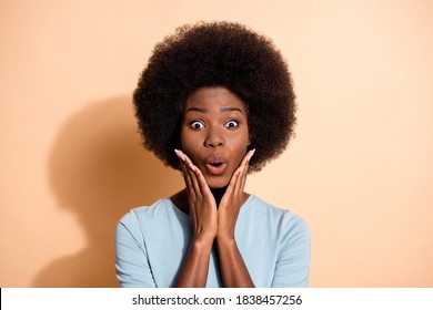 Photo portrait of excited african american woman touching face with hands isolated on pastel beige colored background