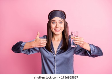 Photo Portrait Of Excited Girl Holding Glass Of Water Raising Thumb Up Isolated On Pastel Pink Colored Background