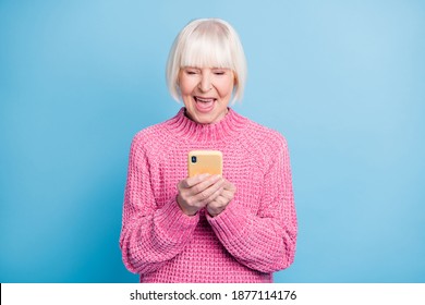 Photo portrait of excited old lady holding phone in two hands isolated on pastel blue colored background - Powered by Shutterstock