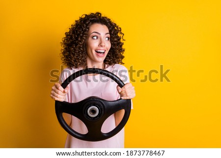 Photo portrait of female driver keeping steering wheel staring at blank space isolated on vivid yellow color background