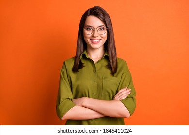 Photo portrait of female freelancer smiling with folded hands wearing glasses green shirt isolated on bright orange color background