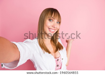 Photo portrait female student taking selfie showing keeping copyspace on hand in white clothes isolated on pastel pink color background