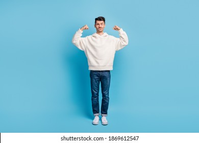 Photo portrait full body view of funny man flexing biceps wearing woolen hoodie isolated on pastel blue colored background