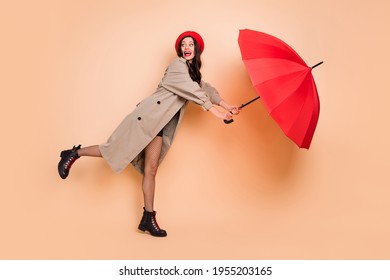 Photo Portrait Full Body View Of Woman Blown Away With Umbrella Isolated On Pastel Beige Colored Background