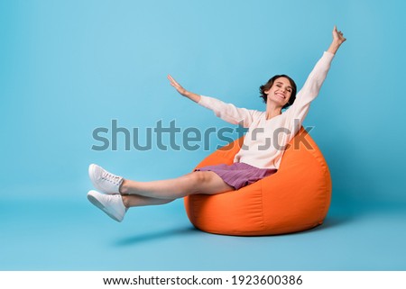 Photo portrait full body view of girl waking up stretching sitting in orange beanbag chair isolated on pastel blue colored background