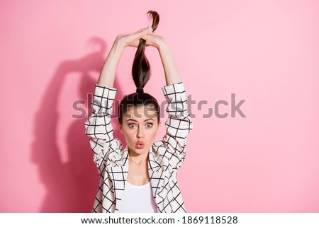 Photo portrait of funky girl playing with ponytail isolated on pastel pink colored background