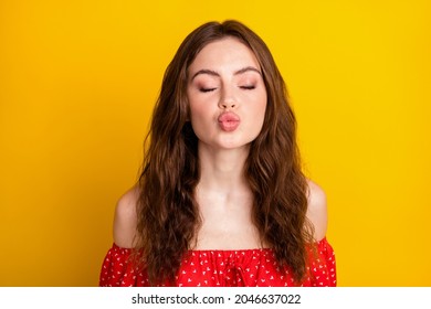 Photo portrait of funky girl sending air kiss pouted lips in red dress isolated on vibrant yellow color background