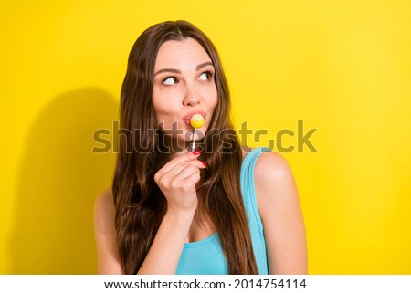 Photo portrait girl in blue singlet smiling eating lollipop looking copyspace isolated vivid yellow color background