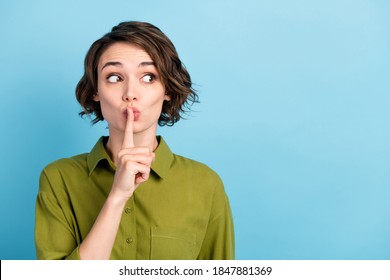 Photo portrait of girl keeping secret put finger near lips showing sign to be silent looking at side wearing formal outfit isolated on blue color background
