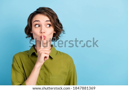 Photo portrait of girl keeping secret put finger near lips showing sign to be silent looking at side wearing formal outfit isolated on blue color background
