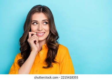 Photo Portrait Of Gorgeous Young Girl Bite Nail Look Empty Space Dressed Stylish Yellow Smart Casual Look Isolated On Blue Color Background