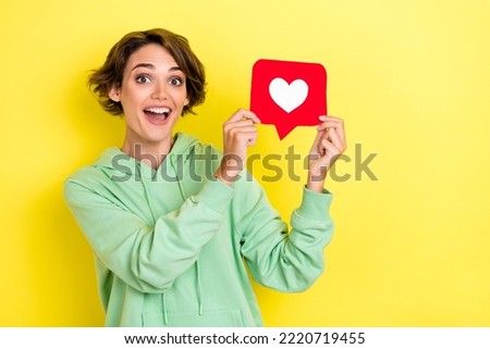 Photo portrait of gorgeous young girl excited hold heart icon smm manager wear trendy green garment isolated on yellow color background