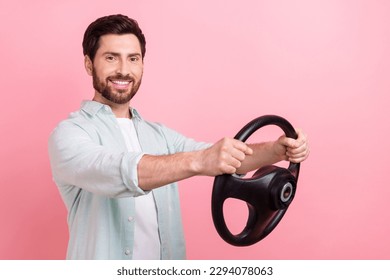 Photo portrait of handsome young guy hold steering wheel rudder cheerful driver wear trendy blue clothes isolated on pink color background