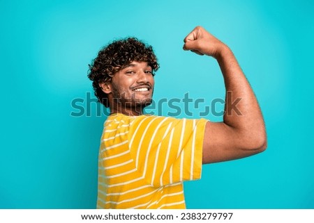 Photo portrait of handsome young guy toothy smile show biceps wear trendy striped yellow outfit isolated on aquamarine color background