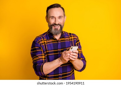 Photo Portrait Of Happy Smiling Man Keeping Mobile Phone Reading News Isolated On Vivid Yellow Color Background