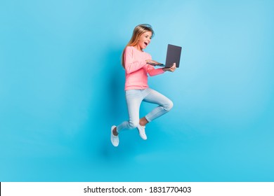 Photo portrait of laughing girl jumping up holding laptop isolated on pastel blue colored background
