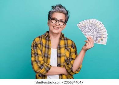 Photo portrait of lovely senior lady holding banknotes money fan wear trendy plaid yellow garment isolated on cyan color background - Shutterstock ID 2366344047