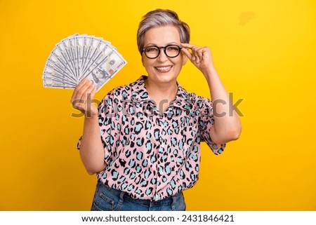Photo portrait of lovely senior lady hold money dollars fan dressed stylish leopard print garment isolated on yellow color background