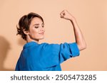 Photo portrait of lovely young lady show strong muscles powerful dressed stylish blue garment isolated on beige color background