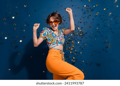 Photo portrait of lovely young lady celebrate victory dancing dressed stylish flared pants garment isolated on dark blue color background - Powered by Shutterstock