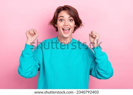 Photo portrait of lovely young lady raise fists excited shout yeah lottery dressed stylish blue garment isolated on pink color background
