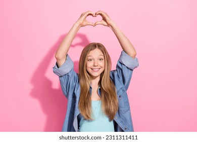 Photo portrait of lovely young teenager lady raise hands heart shape gesture wear trendy jeans garment isolated on pink color background - Shutterstock ID 2311311411