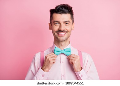 Photo Portrait Of Man Fixing Bowtie Isolated On Pastel Pink Colored Background