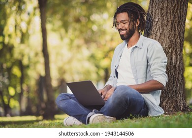 Photo portrait of man in glasses smiling sitting in green park working on laptop smiling - Powered by Shutterstock