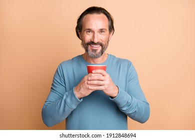 Photo Portrait Of Man Holding Red Mug In Two Hands Isolated On Pastel Beige Colored Background