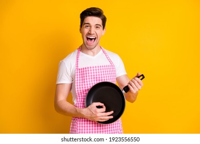 Photo portrait of man playing on frying pan like guitar isolated on vivid yellow colored background