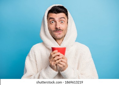 Photo portrait of man tasting delicious coffee holding red mug with two hands wearing woolen hoodie isolated on pastel blue colored background