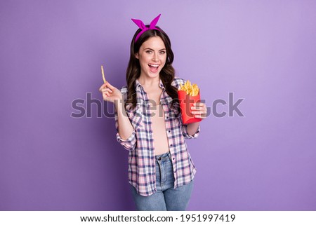Photo portrait of nice girl eating french fries crispy chips wearing headband checkered shirt isolated on vivid purple color background