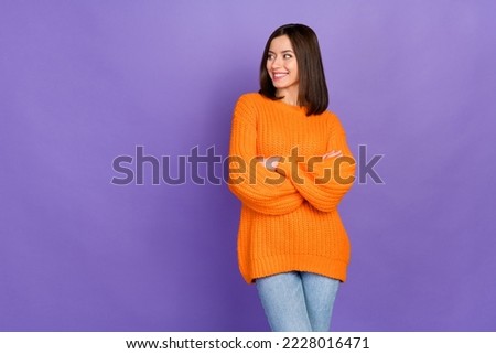 Photo portrait of nice young girl look empty space crossed arms wear trendy knitwear orange garment isolated on violet color background