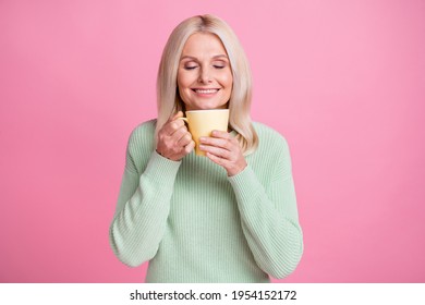 Photo Portrait Of Old Lady Inhaling Aroma Of Fresh Coffee From Yellow Cup Isolated On Pastel Pink Colored Background