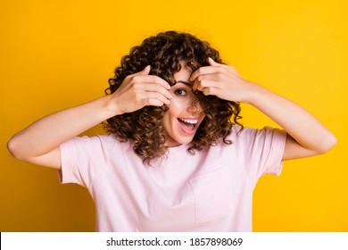 Photo portrait of playful careless girl with curly hairstyle smiling hiding behind hair isolated on vivid yellow color background