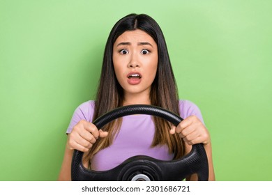 Photo portrait of pretty japanese korean young girl hold steering wheel scared wear trendy purple outfit isolated on green color background