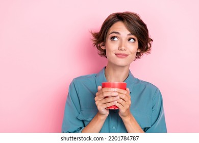 Photo portrait of pretty young girl hold red mug look dreamy empty space dressed trendy blue clothes isolated on pink color background - Powered by Shutterstock
