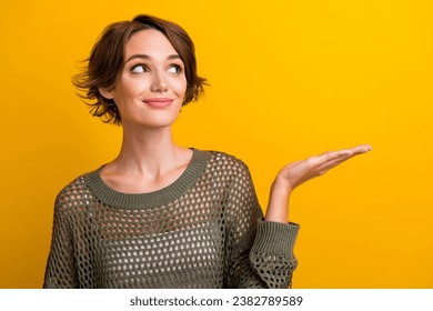Photo portrait of pretty young girl look hold empty space wear trendy knitwear khaki outfit isolated on yellow color background - Shutterstock ID 2382789589