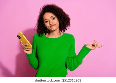 Photo portrait of pretty young girl hold device shrug shoulders wear trendy green outfit isolated on pink color background - Powered by Shutterstock