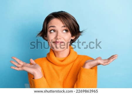Photo portrait of pretty young girl shrug shoulders dont care empty space dressed stylish orange outfit isolated on blue color background