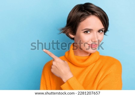 Photo portrait of pretty young girl point finger empty space recommend dressed stylish orange outfit isolated on blue color background