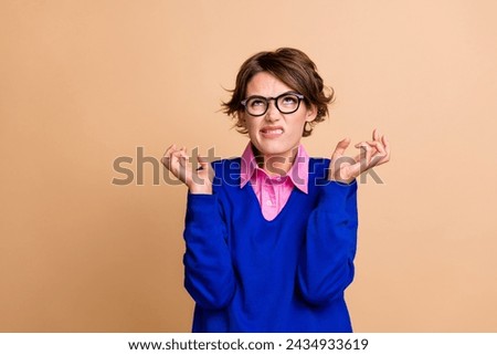 Photo portrait of pretty young girl look up angry empty space mad expression dressed stylish blue outfit isolated on beige color background