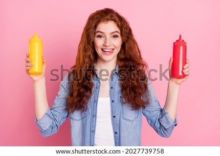 Photo portrait red haired girl showing tongue keeping ketchup mustard sauces isolated pastel pink color background