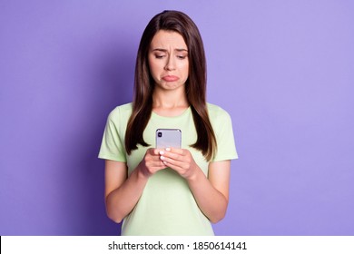 Photo portrait of sad upset girl typing texting message on mobile phone crying isolated on bright purple color background