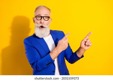 Photo Portrait Of Senior Man In Blue Suit Amazed Pointing Fingers Empty Space Isolated Bright Yellow Color Background